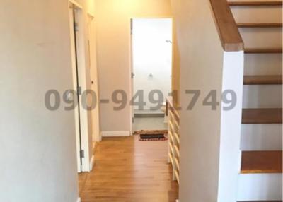 Bright hallway interior with wooden floors and staircase leading to upper level