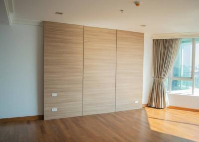 Spacious bedroom with large wooden wardrobe and ample natural light