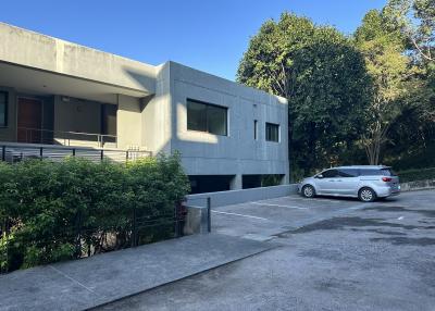 Modern building exterior with parking space and lush greenery