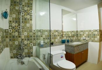 Spacious bathroom with patterned tile walls, modern fixtures, and a bathtub