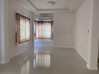 Spacious and well-lit living room with glossy tiled flooring and large windows