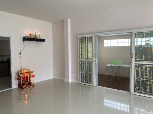 Spacious and bright living room with glossy tiled flooring and a decorative altar