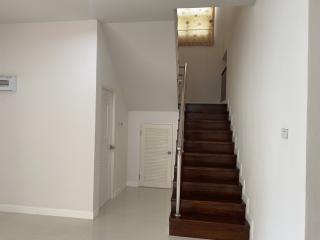 Interior view of a residential building with a wooden staircase, white walls and doors