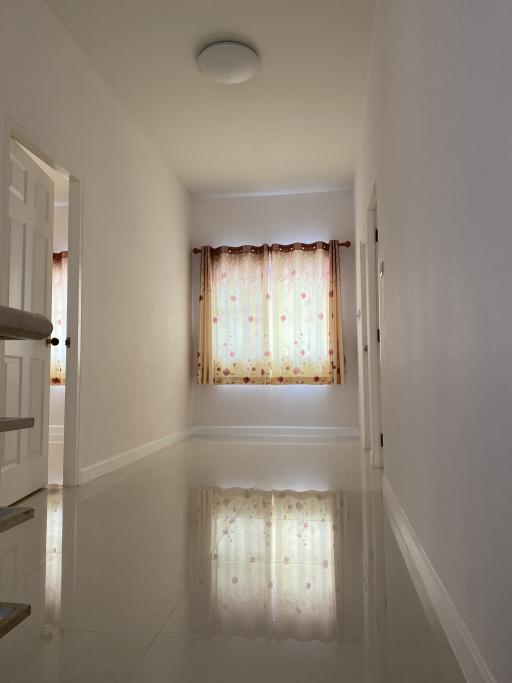 Bright hallway with tiled floors and window curtains