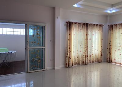 Spacious living room with tiled flooring, large windows, and elegant curtains