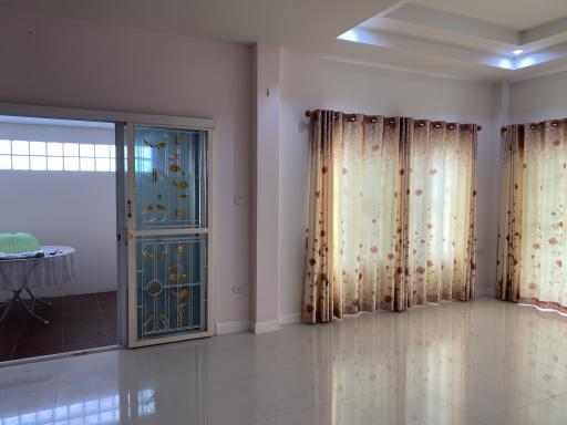 Spacious living room with tiled flooring, large windows, and elegant curtains