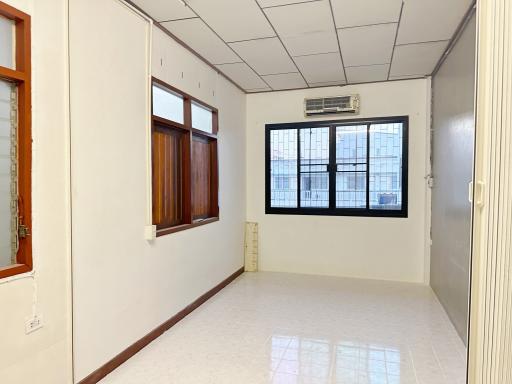 Spacious empty room with tile flooring, window, and air conditioning unit