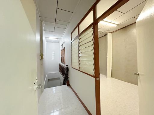 Brightly lit hallway with tiled flooring and glass panel doors
