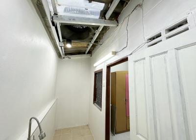 Narrow building hallway with exposed pipes and unfinished ceiling