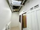 Narrow building hallway with exposed pipes and unfinished ceiling