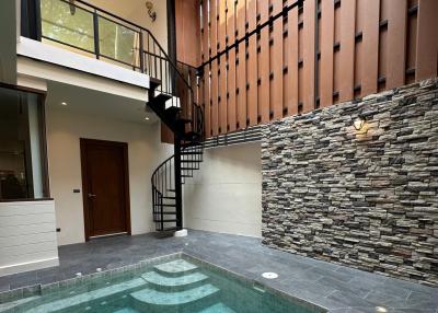 Modern house entrance with spiral staircase and small pool