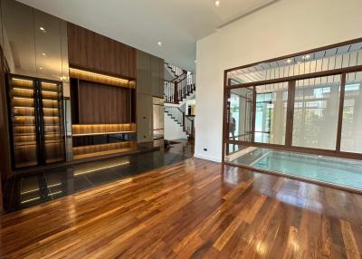 Spacious living area with hardwood floors, modern staircase, and pool view