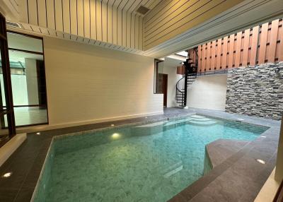 Indoor swimming pool with stone feature wall and staircase