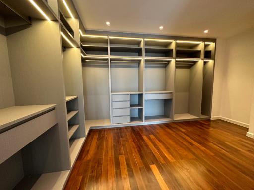 Spacious bedroom with custom shelving and hardwood floors