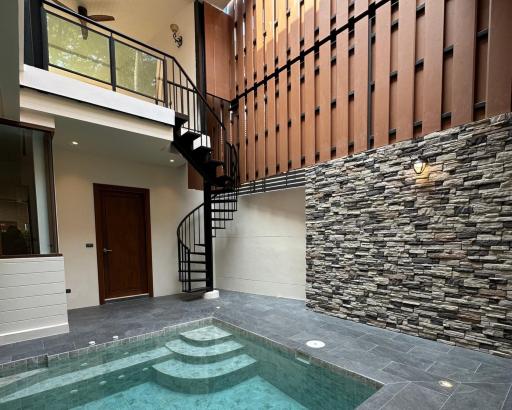 Modern home entrance with spiral staircase and small pool