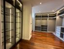 Spacious walk-in closet with custom shelving and hardwood floors