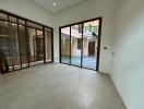 Spacious empty room with large glass doors and tiled flooring