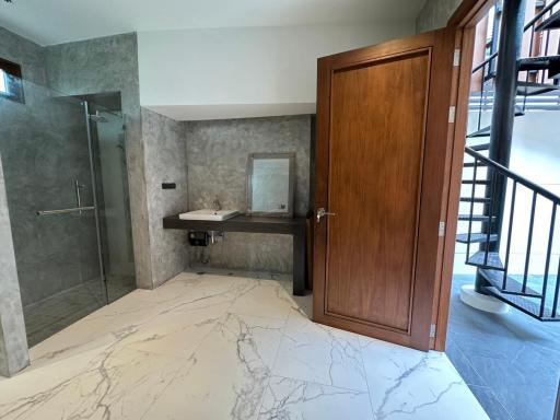 Modern bathroom interior with marble flooring, glass shower area, and wooden door