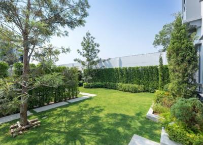 Well-maintained garden with lush greenery and seating area next to a modern building