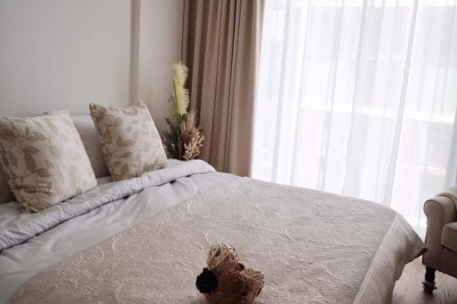 Cozy bedroom with a made bed, neutral color scheme, and ample natural light