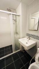 Modern bathroom with glass shower cubicle, ceramic sink, and toilet