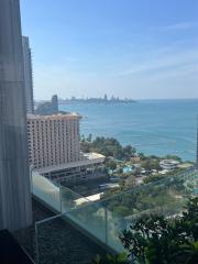 Coastal view from a high-rise apartment balcony overlooking the sea and city skyline