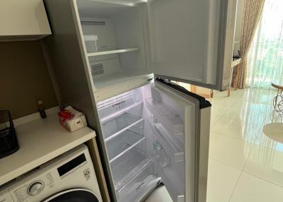 Open refrigerator next to a washing machine in a modern kitchen