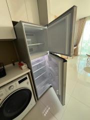 Open refrigerator next to a washing machine in a modern kitchen