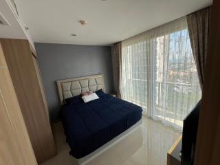 Spacious bedroom with a large bed, natural light, and city view