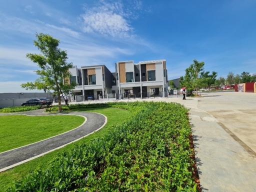 Modern townhouses with landscaped front yards under clear blue sky