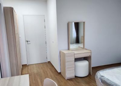 Modern bedroom with wooden flooring, white walls, and a vanity table