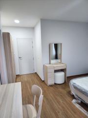 Modern bedroom with wooden flooring, white walls, and a vanity table