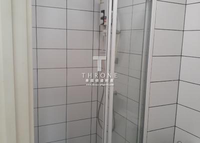 Small white tiled bathroom with glass shower door and toilet