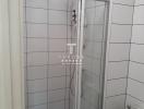 Small white tiled bathroom with glass shower door and toilet