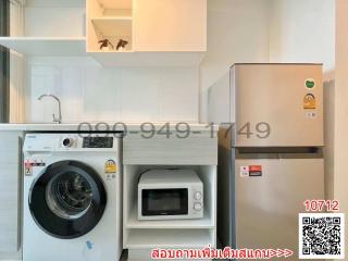 Compact kitchen with modern appliances including a washing machine, refrigerator, and microwave