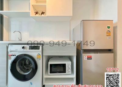 Compact kitchen with modern appliances including a washing machine, refrigerator, and microwave