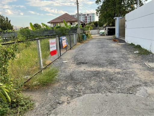Chain-link fenced driveway leading to residential property with signage