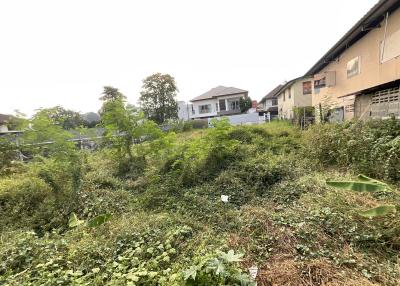 Exterior view of a property with vegetation in front and houses in the background