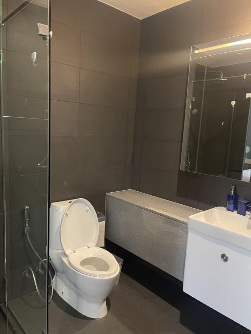 Modern bathroom with glass shower enclosure and dark tiles