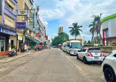 Urban street view with commercial buildings and parked vehicles under a clear blue sky