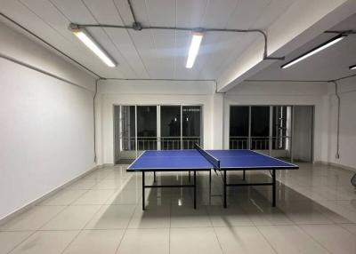 Spacious recreation room with table tennis setup, ample lighting, and large windows