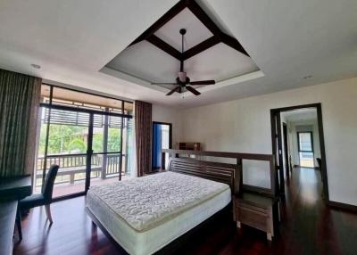 Spacious bedroom with a high ceiling, modern furnishings, and ample natural light
