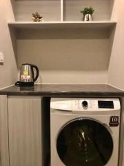 Compact laundry room with washing machine, shelving, and countertop space
