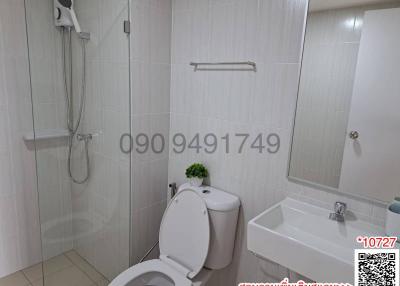 Modern white-tiled bathroom with shower, toilet, and basin