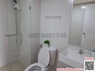 Modern white-tiled bathroom with shower, toilet, and basin