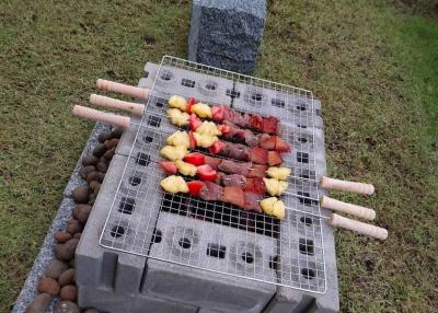 Outdoor barbecue grill setup with skewers on a lawn