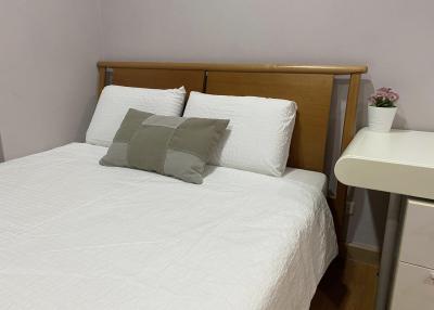 A neatly made bed with white bedding and a wooden headboard in a bedroom