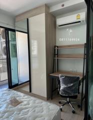 Compact bedroom with large window, air conditioning, and office chair