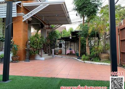 Spacious patio area with terracotta tiles and artificial grass