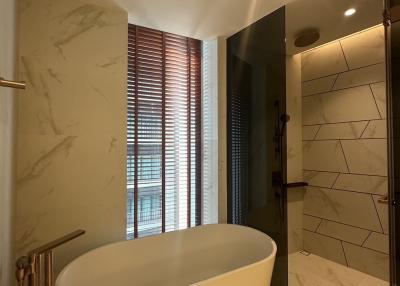 Elegant bathroom with freestanding tub, marble tiling, and natural light